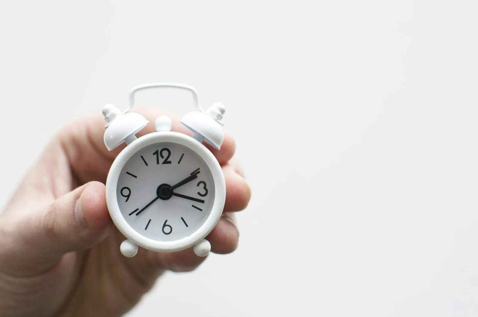 A minimalist alarm clock on a nightstand with soft morning light